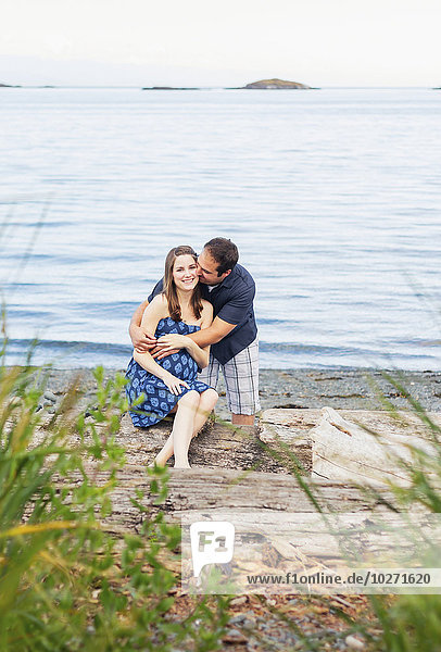 'A young couple poses for pregancy portraits on a beach at the ocean  expecting their first child for their family; Nanaimo  British Columbia  Canada'