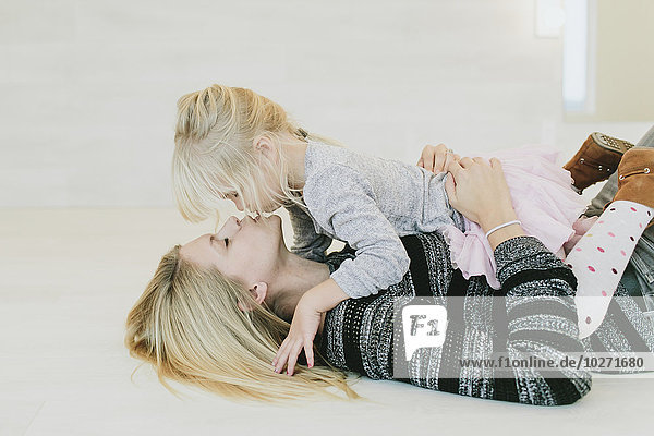 Eine Mutter und ihre kleine Tochter teilen einen Kuss