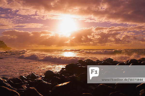 Sonnenaufgang und Wellen  die gegen die Felsen schlagen  Kealia Beach; Kauai  Hawaii  Vereinigte Staaten von Amerika'.