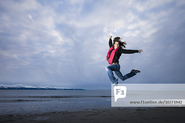 Junge Frau spielt und springt auf der Nehrung von Homer  Kenai-Halbinsel  Süd-Zentral-Alaska