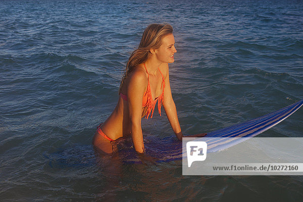 Jugendliches Mädchen am Strand mit ihrem Surfbrett; Kailua  Insel Hawaii  Hawaii  Vereinigte Staaten von Amerika'.