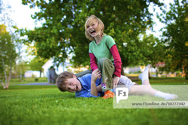 'A boy and girl wrestling on the grass; Picton Ontario Canada'