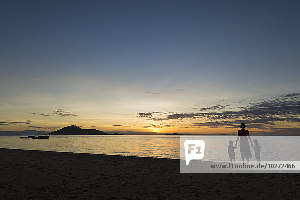 'Silhouette of mother with boy and girl on beach at Cape Maclear at sunset  Lake Malawi; Malawi'
