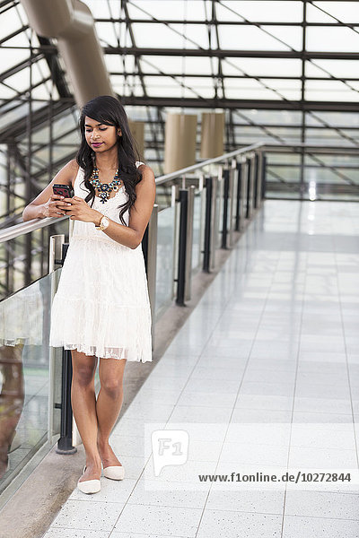 'Young professional businesswoman texting on her smart phone in office building; Edmonton  Alberta  Canada'