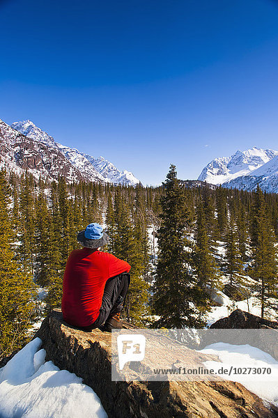 Ein Mann sitzt im Eagle River Valley an einem sonnigen Wintertag in South Central Alaska; Alaska  Vereinigte Staaten von Amerika'.