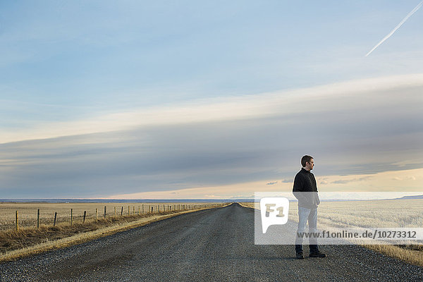 'Man standing on a rural road; Claresholm  Alberta  Canada'
