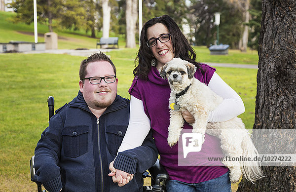 Behinderter Mann  seine Frau und ihr Hund posieren für ein Familienporträt in einem Park im Herbst; Edmonton  Alberta  Kanada'.