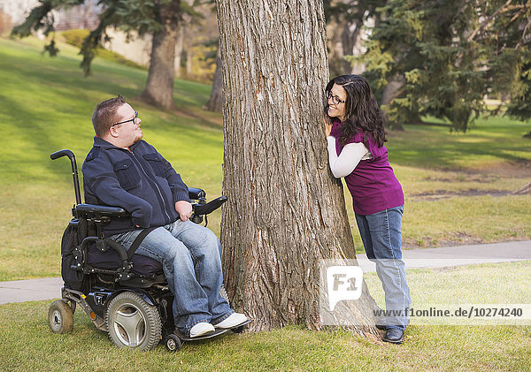'Disabled husband talking with his wife in a park in autumn; Edmonton  Alberta  Canada'
