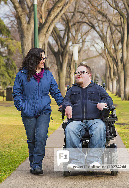 'Disabled husband talking with his wife while walking in a park in autumn; Edmonton  Alberta  Canada'