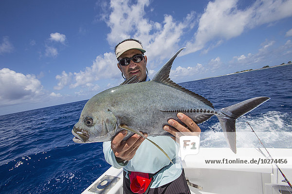Fischer hält einen frisch gefangenen Jackfish; Tahiti'.