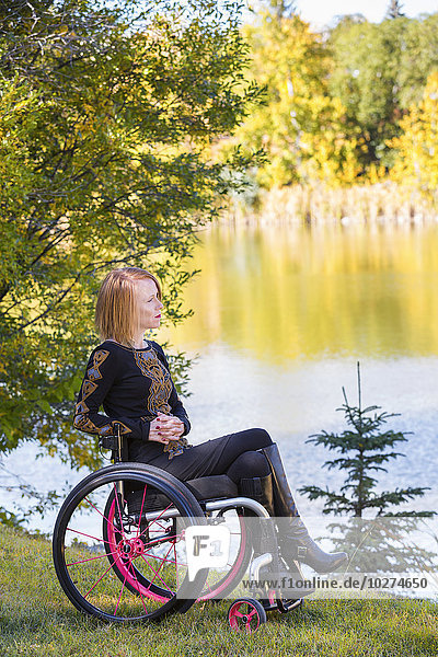 Junge behinderte Frau im Rollstuhl in einem Stadtpark im Herbst; Edmonton  Alberta  Kanada'.