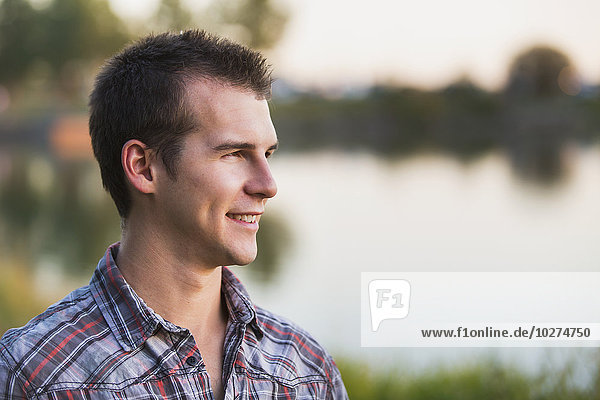 'Portrait of a young man beside a lake in autumn; St. Albert  Alberta  Canada'