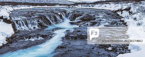 Türkisfarbenes Wasser  das über Felsen in einen Fluss fließt; Bruarfoss  Island'.
