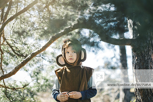 Thoughtful girl in monkey suit standing by tree at yard