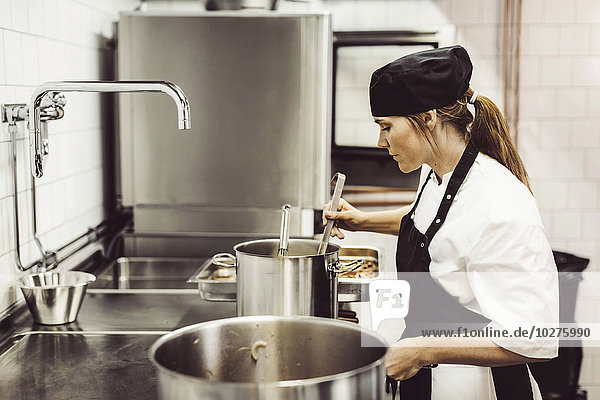 Side view of female chef preparing food in kitchen