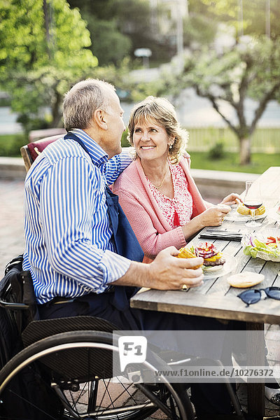Ein glückliches reifes Paar,  das sich beim Essen im Hof ansieht.