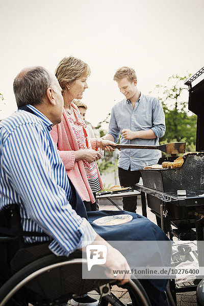 Großeltern mit Brüdern beim Grillen auf dem Hof