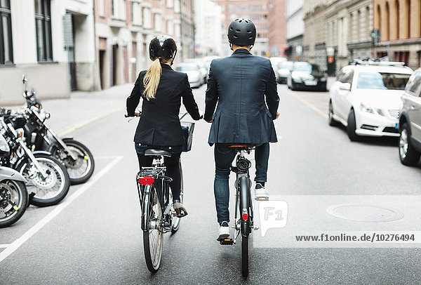 Rückansicht von Geschäftsleuten beim Fahrradfahren auf der Straße