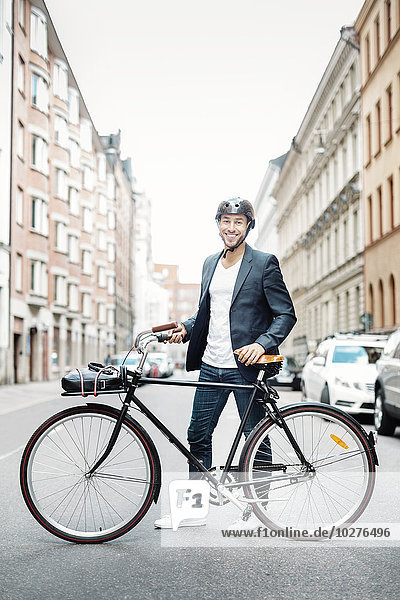 Portrait of happy businessman with bicycle standing on city street