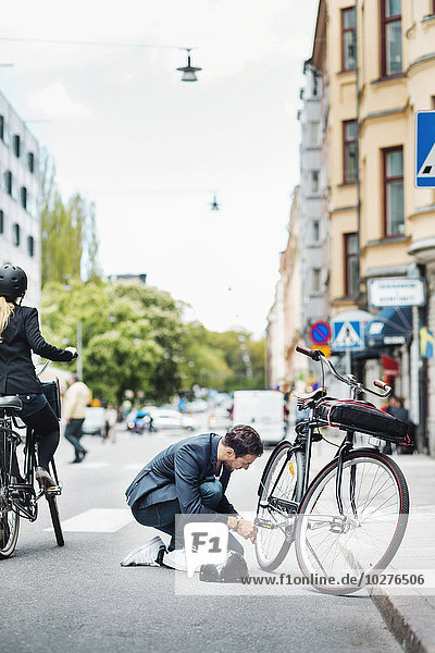 Geschäftsmann repariert Fahrrad auf der Straße