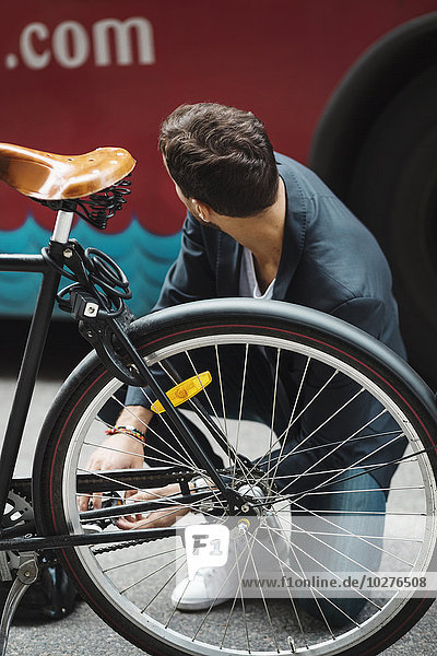Geschäftsmann repariert Fahrrad auf der Straße