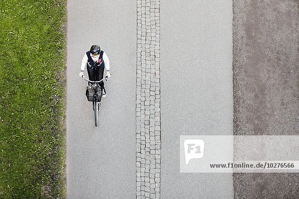 Hochwinkelansicht der Geschäftsfrau beim Radfahren auf der Straße