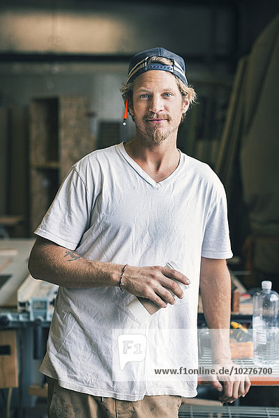 Portrait of confident carpenter standing in workshop