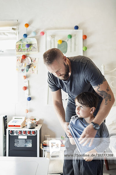 Man assisting son in getting dressed at home