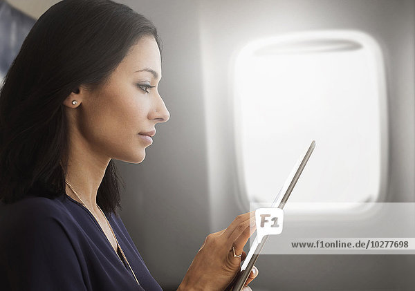 Junge Frau benutzt Tablet im Flugzeug