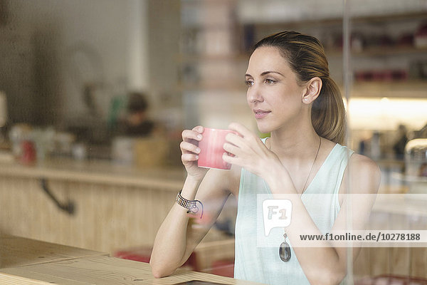 Frau hält Kaffeetasse in einem Cafe