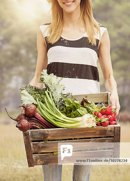 Frau trägt frisches Gemüse in einer Kiste