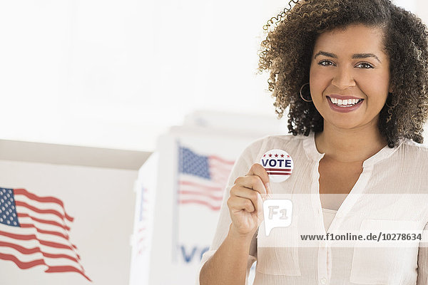 Junge Frau hält Wahlplakette und lächelt