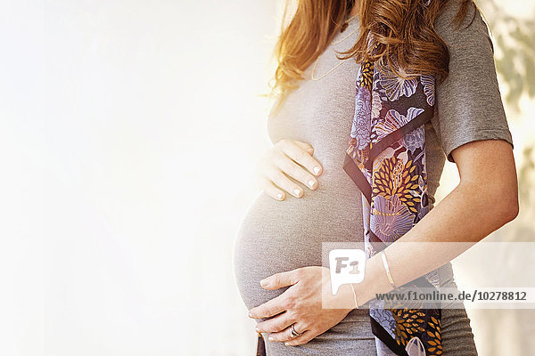 Mittelteil einer schwangeren Frau im Freien