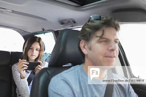 Girl (10-11) texting in back seat