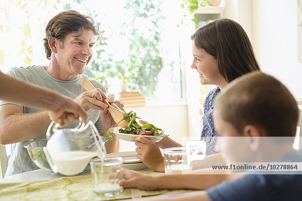 Kinder (8-9  10-11) essen Salat mit ihren Eltern