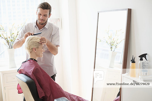 Hairdresser combing woman's hair