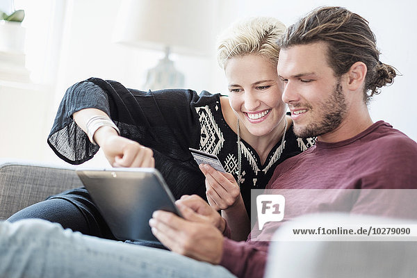 Couple using tablet pc on sofa