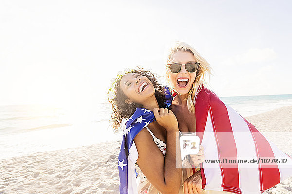 Female friends on beach with American flag