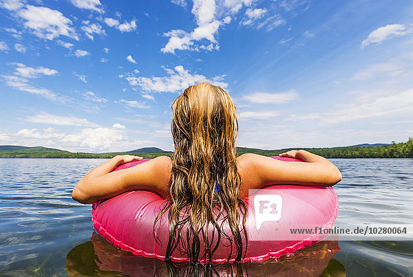 Junge Frau entspannt sich auf einem See in einem Pool-Floß