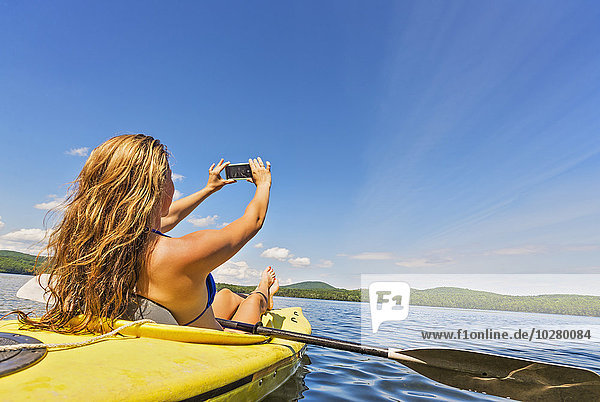 Junge Frau macht Selfie im Kajak auf dem See