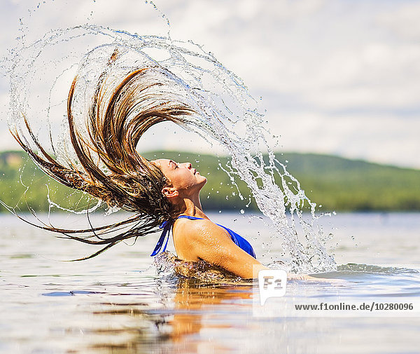 Junge Frau wirft ihr Haar im See zurück