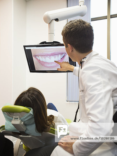 Zahnarzt und Patient schauen auf den Bildschirm