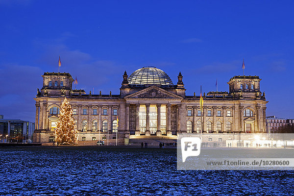 Beleuchtetes Bundestagsgebäude und verschneiter Rasen