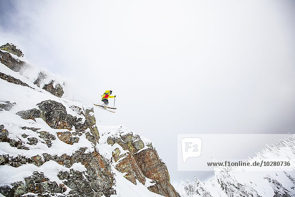 Skifahrer springt von einem felsigen Berg