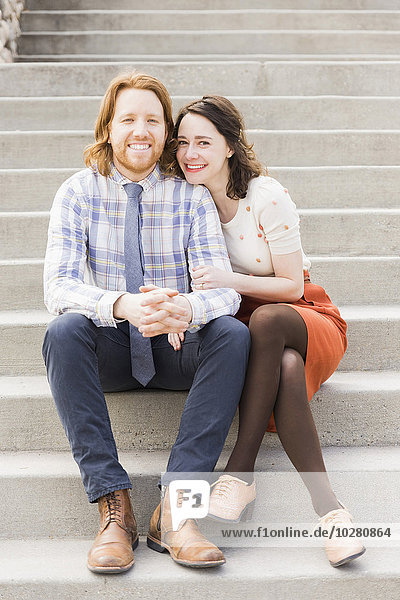 Lächelndes Paar auf Stufen sitzend