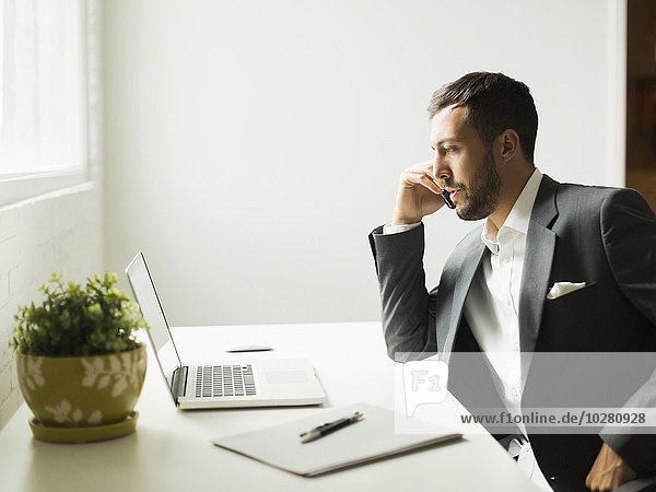 Young man sitting at desk and looking at laptop