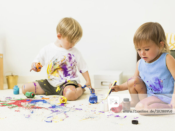 Children (2-3) painting on carpet