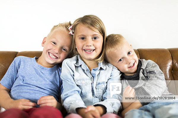 Lächelnde Kinder (2-3  4-5) auf dem Sofa sitzend