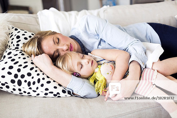 Mother and daughter (2-3) sleeping on sofa