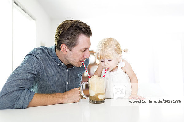 Vater trinkt Milchshake mit Tochter (2-3)